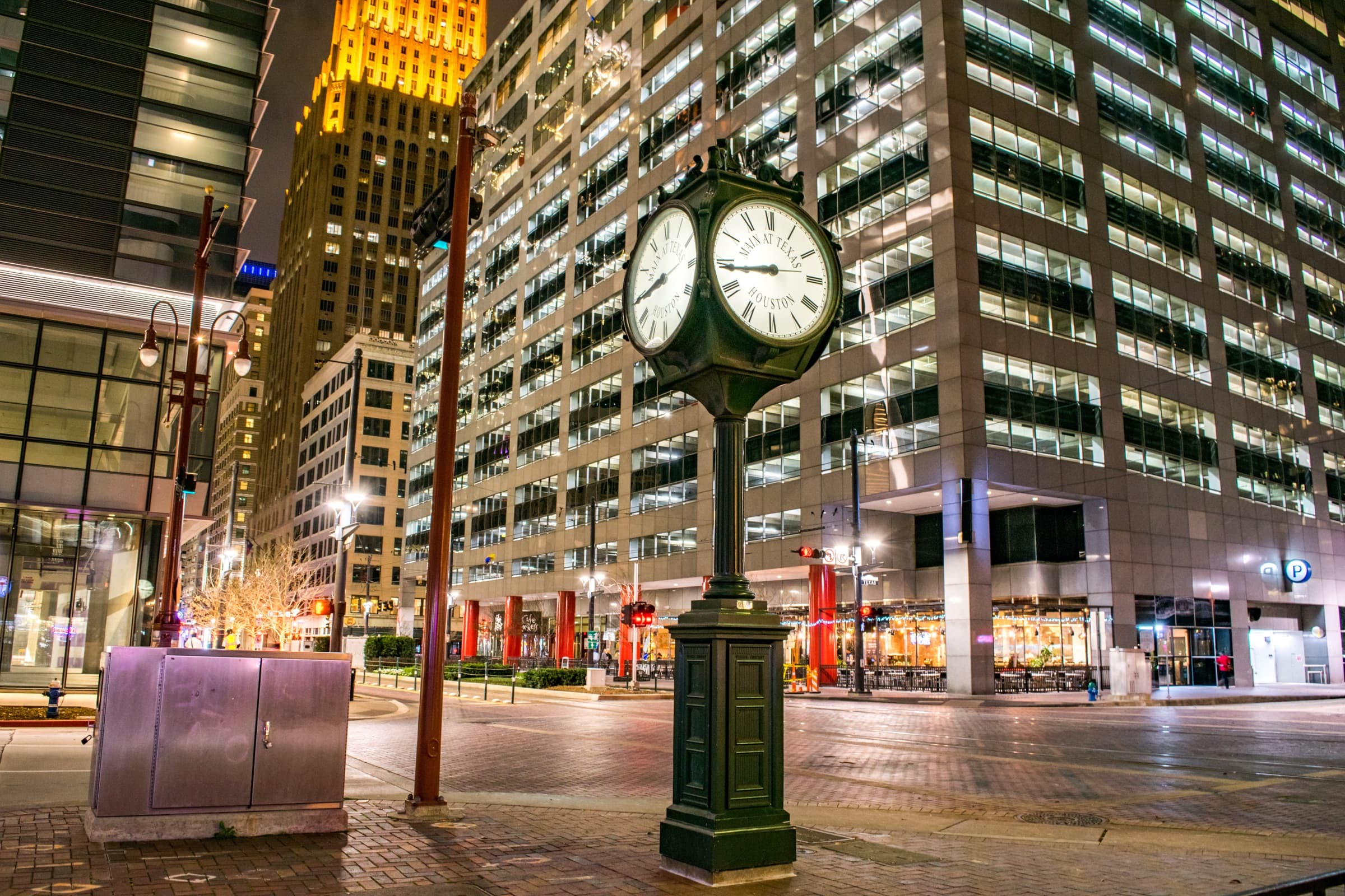 The Main at Texas street clock in downtown Houston at night, with the Niels Esperson building lit behind it