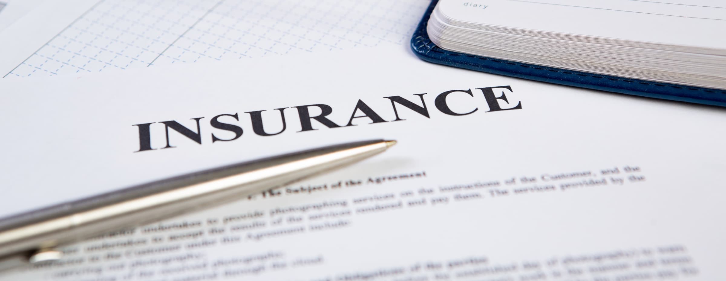 An insurance policy document on a desk with a pen resting across it