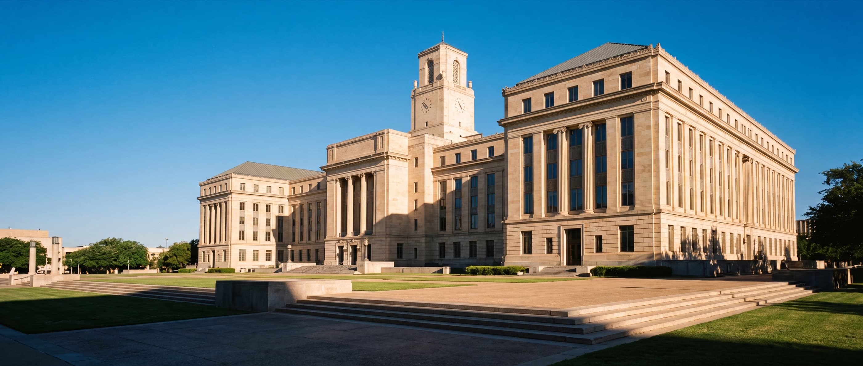 A dignified limestone courthouse with a clock tower in bright daylight